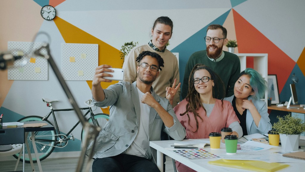Five colleagues taking a group selfie at a desk in a colourful office